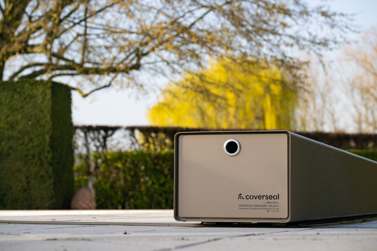 Vue aérienne d’une maison en pierre avec piscine équipée d’une couverture Coverseal grise, intégrée harmonieusement dans la terrasse en pierre claire.
